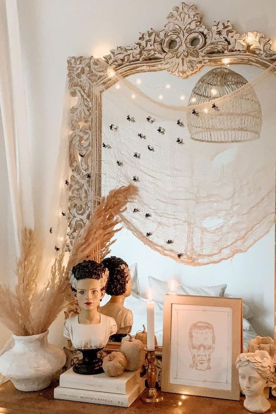 a mirror in a white shabby chic frame, with lights, cheesecloth with black spiders is a cool idea for Halloween