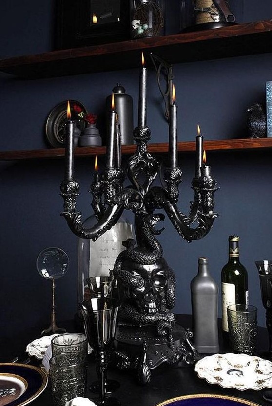a black skull covered with a snake candelabra with black candles is an adorable decoration to rock at Halloween