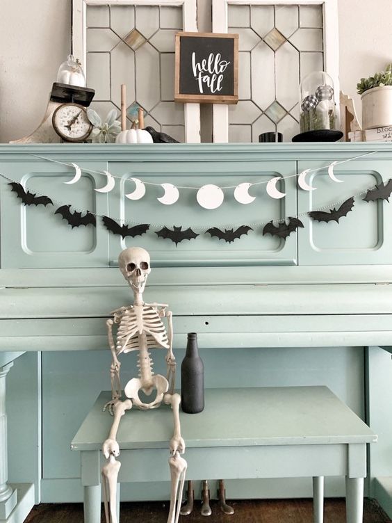 a black bat garland paired with a white moon phase one are a cool and simple combo for Halloween decor
