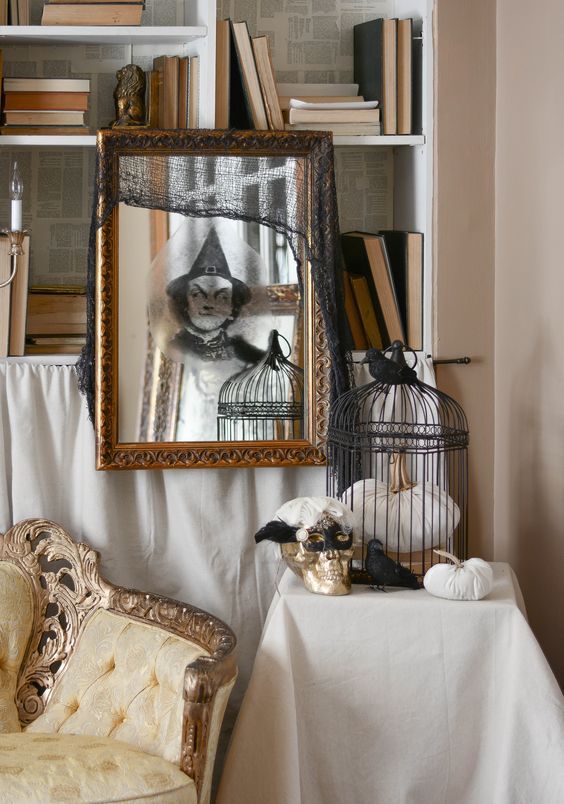 a mirror in a vintage gilded frame with a ghost sticker and a black cheesecloth piece is great for Halloween