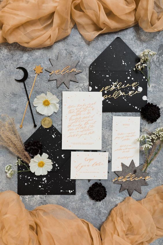 a beautiful celestial Halloween party invitations in black, white and with gold calligraphy, with splattered paint