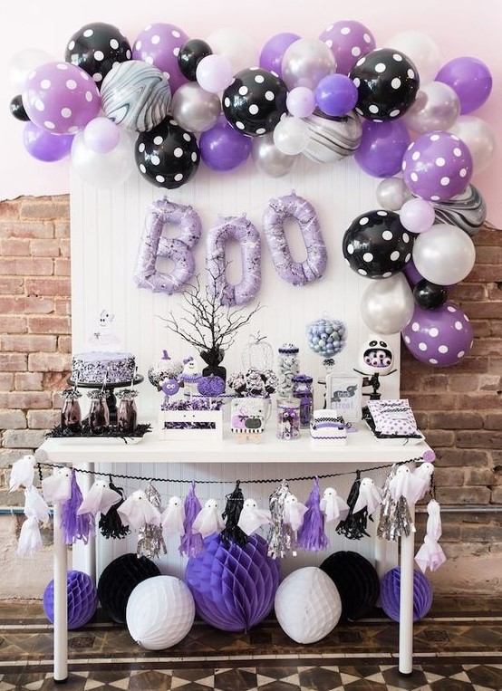 a black, white and purple Halloween sweets table with a ghost garland, lots of balloons and balloon letters