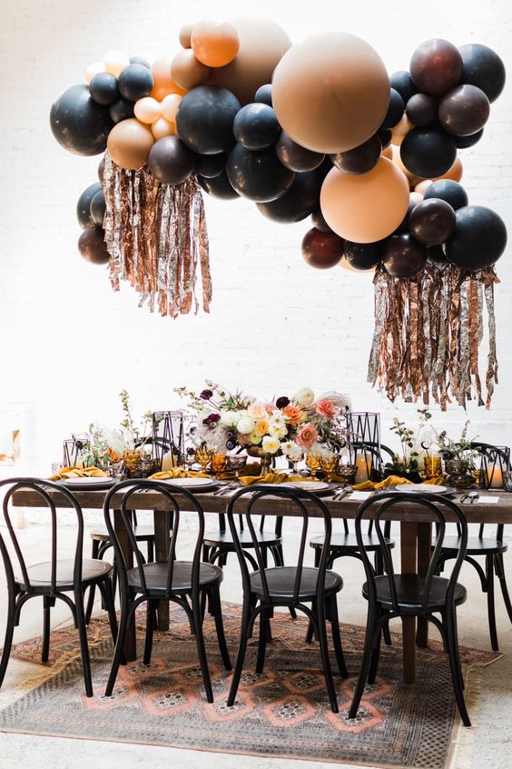 a celestial Halloween party tablescape with bold blooms, a balloon overhead installation, yellow napkins and black chairs