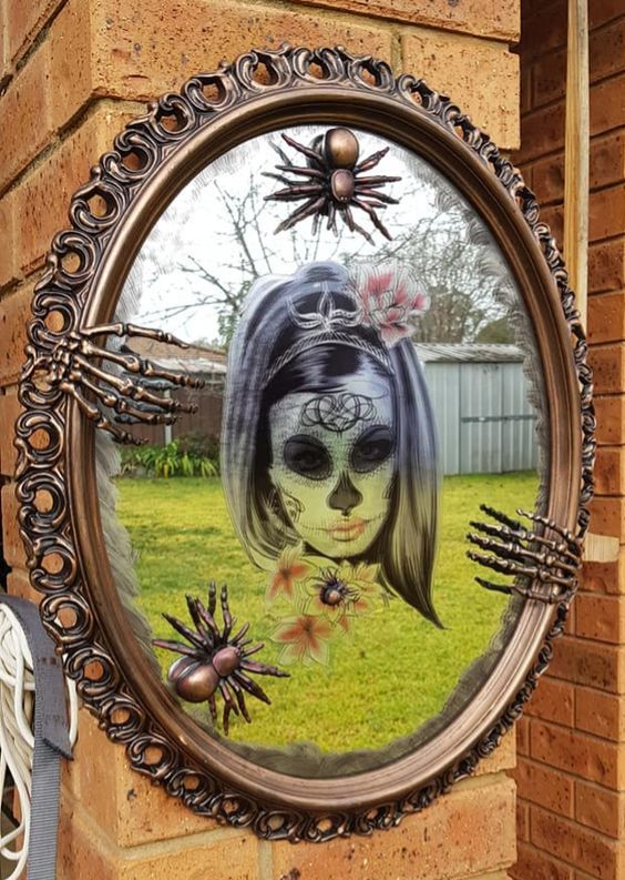 bold Halloween mirror decor with a sugar skull, skeleton hands and copper spiders is a cool and bright idea