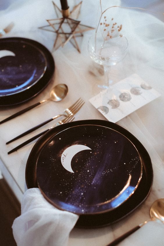 a celestial Halloween party tablescape with neutral textiles, refined deep purple plates with stars and moons is wow