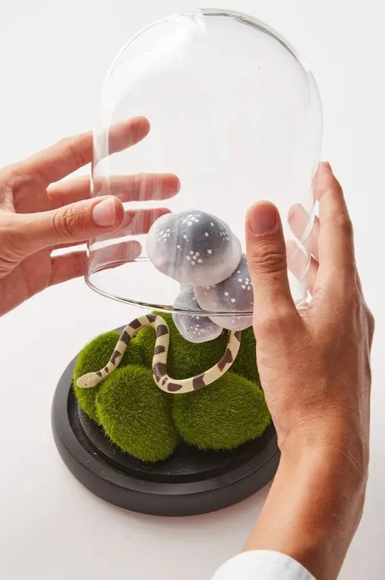 a cool Halloween cloche with moss, a little snake and mushrooms is a creative decoration for the party
