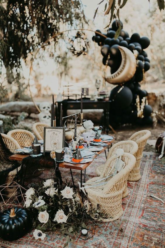 a celestial Halloween tablescape with a black pumpkin, neutral blooms, black candles and lovely balloon decorations at the back