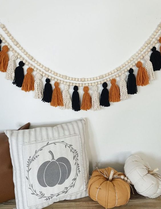 a creative boho Halloween garland of wooden beads, white, orange and black twine tassels is not difficult to make