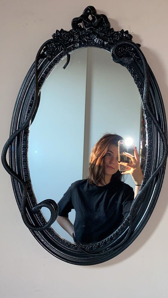 a black frame mirror with some snakes on the frame is a chic and spooky Halloween decoration