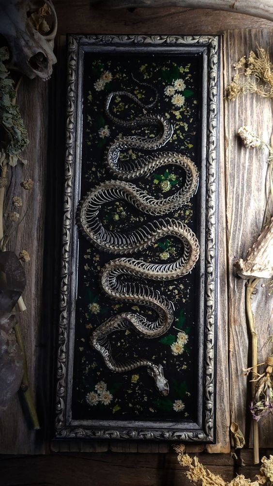 a Halloween artwork with some dried flowers and a snake skeleton is a unique decor idea, and you make one yourself
