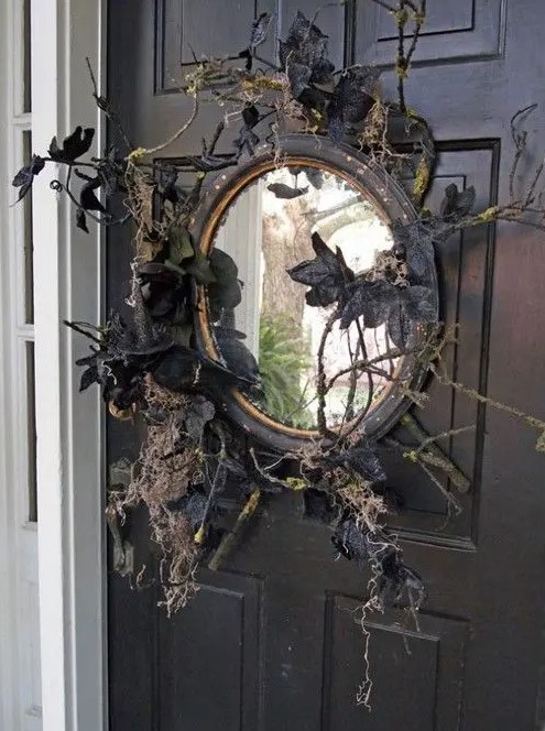 a black mirror with branches, twigs, black leaves and blackbirds is a lovely front door decoration for those who love vintage Halloween decor
