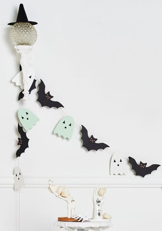 a Halloween garland of black bats and mint green and white ghosts is a cool and easy decor idea for your space