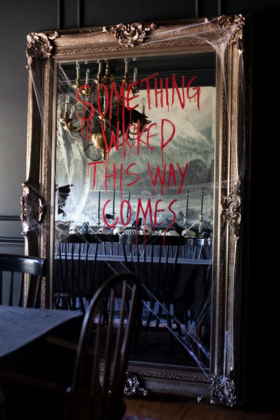 a floor mirror with realistic spiderweb and a quote done with blood is a bold and spooky solution for Halloween decor