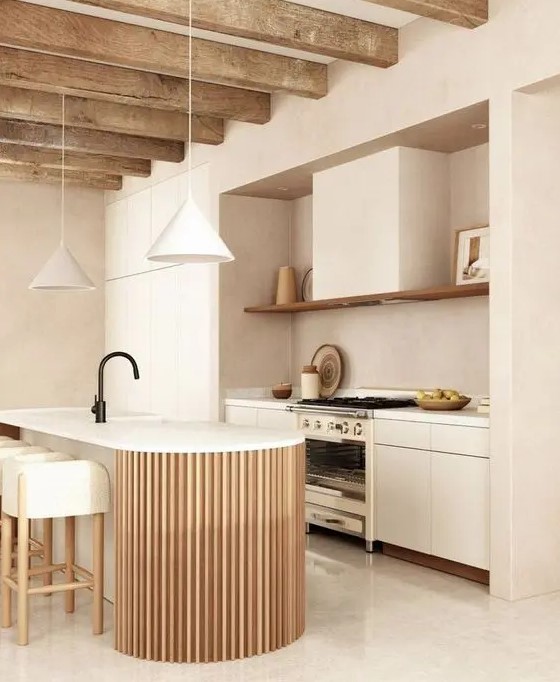 a neutral warm-colored kitchen with sleek cabinets, an open shelf, a curved and fluted kitchen island and pendant lamps