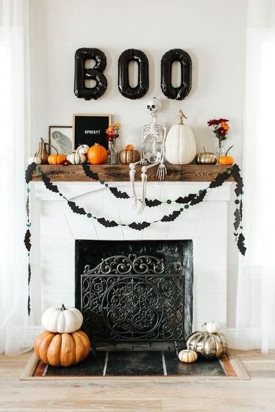 a lovely Halloween fireplace with stacked pumpkins, black bat buntings, pumpkins and a skeleton on the mantel and black balloon letters