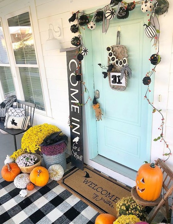 a mini black and white pumpkin garland, bright fall blooms in baskets, bright pumpkins and a plaid mat
