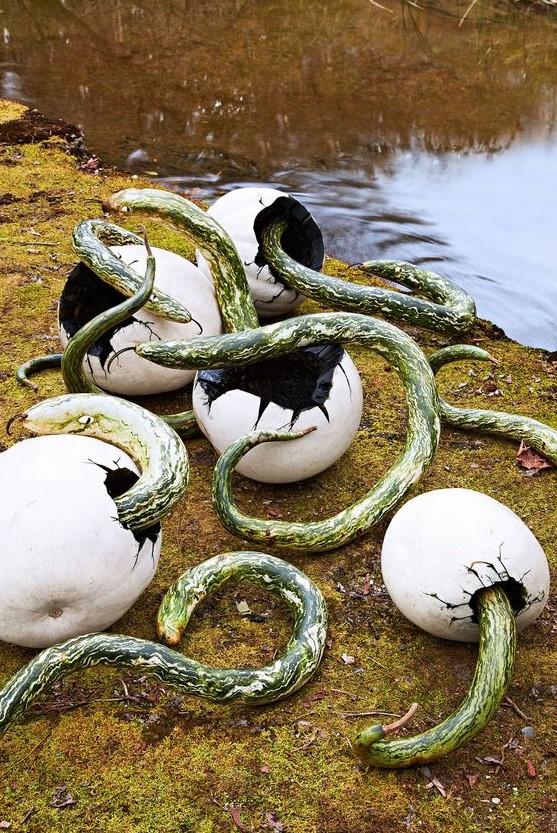 pumpkins styled as large eggs and faux green snakes coming out of them for a super scary and a bit disgusting Halloween outdoor scene
