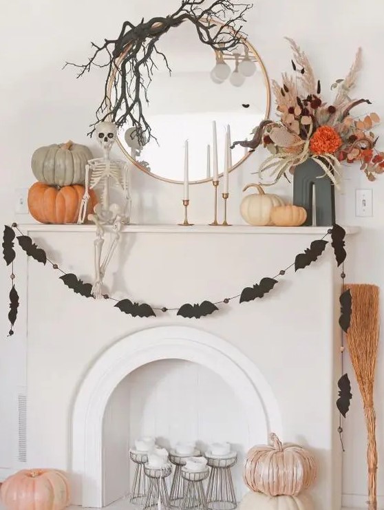 a round mirror with black branches on top, a black bat garland, stacked pumpkins, a dried flower arrangement and a skeleton