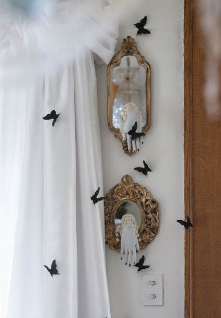 small mirrors in vintage frames with ghost hands and black butterflies around is a cool and bold idea