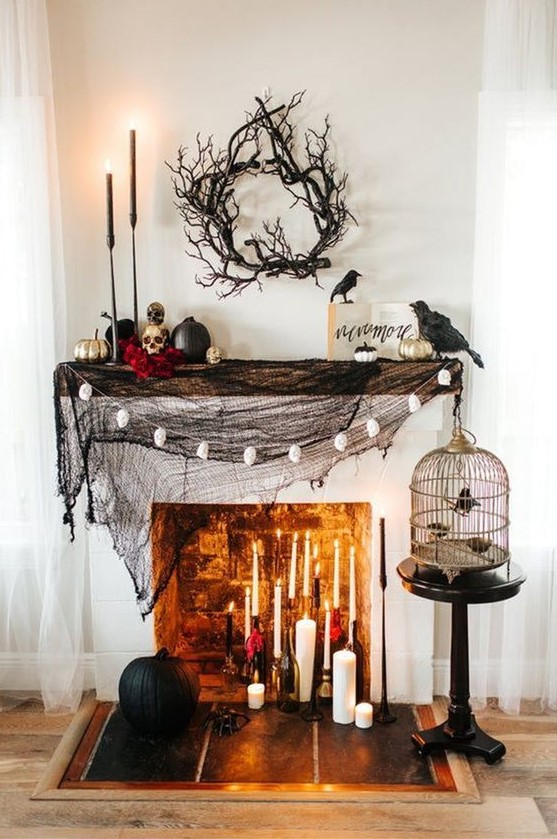 a stylish Halloween mantel with black spiderweb, lots of candles, skulls and black and gilded pumpkins plus blackbirds