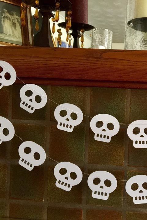 a super easy to make white paper skull garland will help you decorate a mantel, a porch, an entryway or any other space