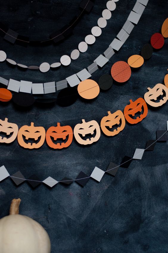 an arrangement of Hallwoeen paper garlands with rhombs, polka dots, squares and jack-o-lanterns