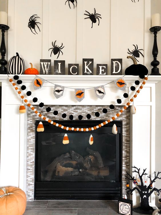 Halloween garlands with candy corns, kisses and black pompoms are great for styling a Halloween mantel