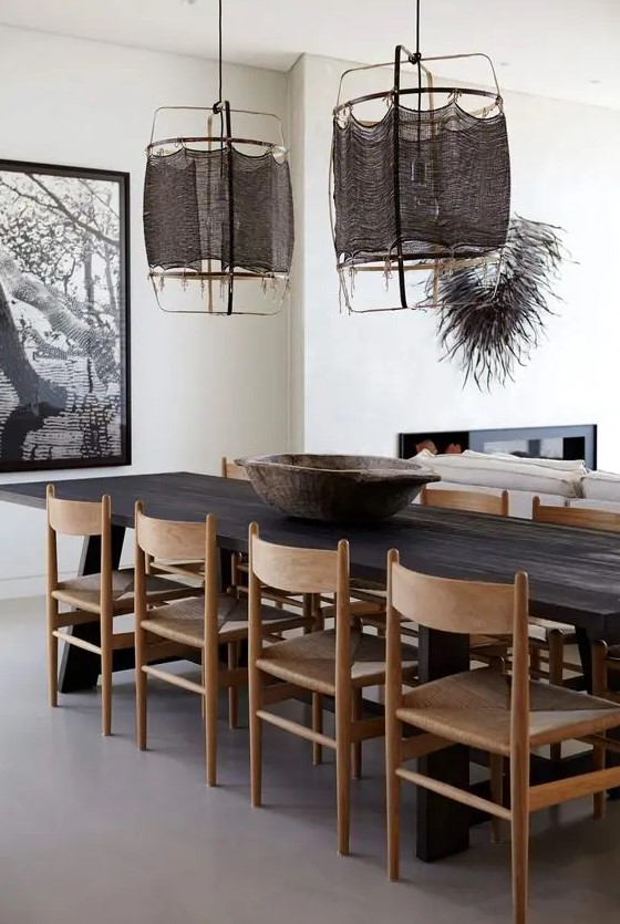 a bold and catchy dining space with a dark-stained dining table, light-stained chairs, dark pendant lamps and a bold artwork