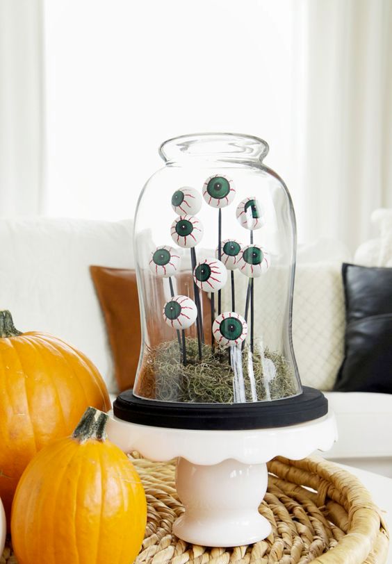 a bright Halloween cloche with moss, eyeballs on sticks is a cool and fun decoration, suitable for kids' parties