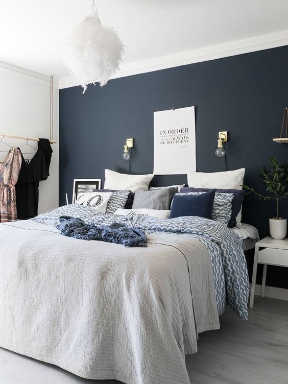 a-catchy-modern-bedroom-with-a-midnight-blue-accent-wall-a-bed-with-navy-and-white-bedding-white-nightstands-and-a-fluffy-pendant-lamp.jpg