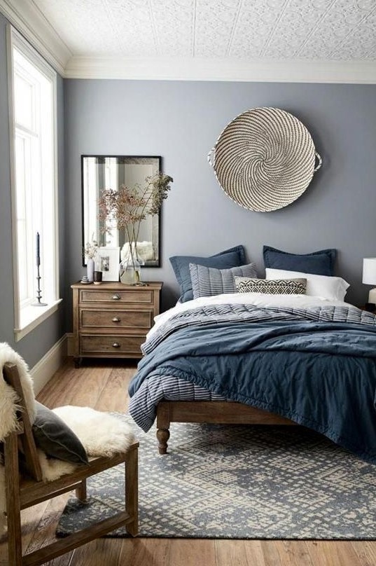 a-chic-blue-bedroom-with-stained-wooden-furniture-a-woven-basket-on-the-wall-blue-bedding-a-mirror-a-boho-rug-and-some-faux-fur.jpg
