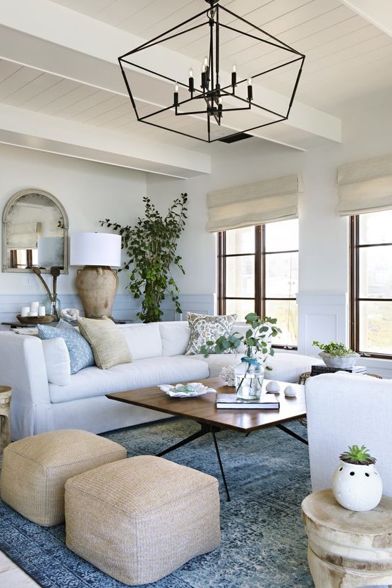 a chic coastal living room with touches of blue and light blue, creamy furniture and tan items plus a dirftwood lamp