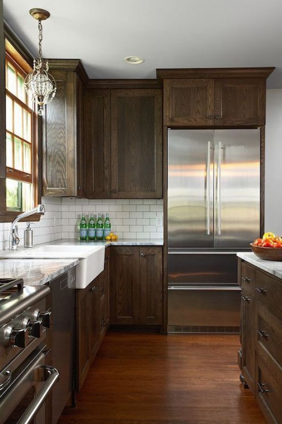 a dark-stained kitchen with shaker cabinets, grey stone countertops, a white subway tile backsplash and a chic pendant lamp