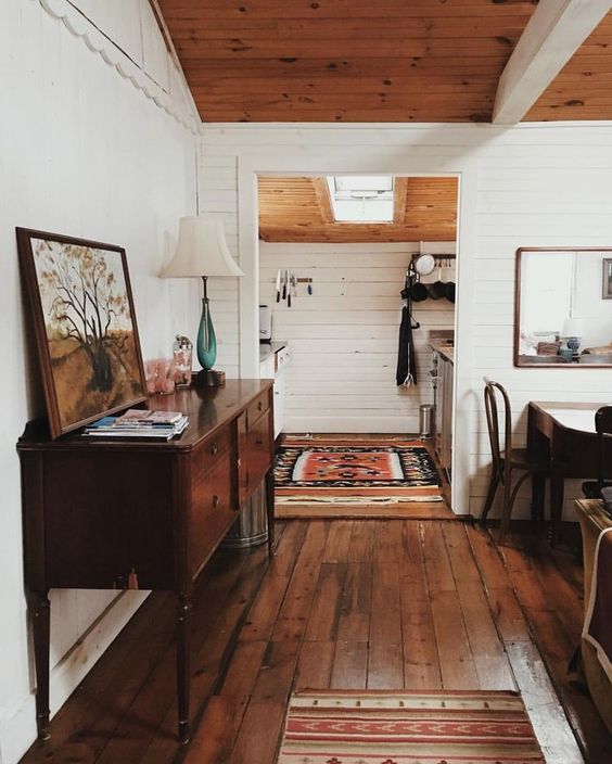 a farmhouse meets boho space with a rich-stained floor, dark-stained furniture and some boho textiles and artwork