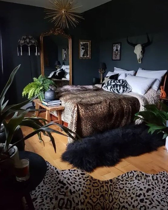 a glam moody bedroom with wooden furniture, an oversized mirror in a gold frame, a sunburst chandelier, faux animal skis