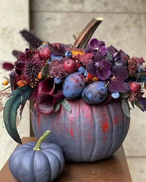 a jaw-dropping grey pumpkin decorated with dark burgundy and purple blooms, plums, berries and apples and dried grasses