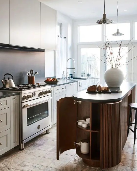 a lovely Scandinavian kitchen dove grey cabinets, a matte black backsplash, a ridged curved kitchen island and pendant lamps over it