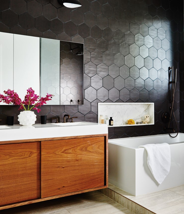 a modern bathroom with soot hexagon tiles, neutral tiles, a rich-stained vanity, a tub and a mirror cabinet