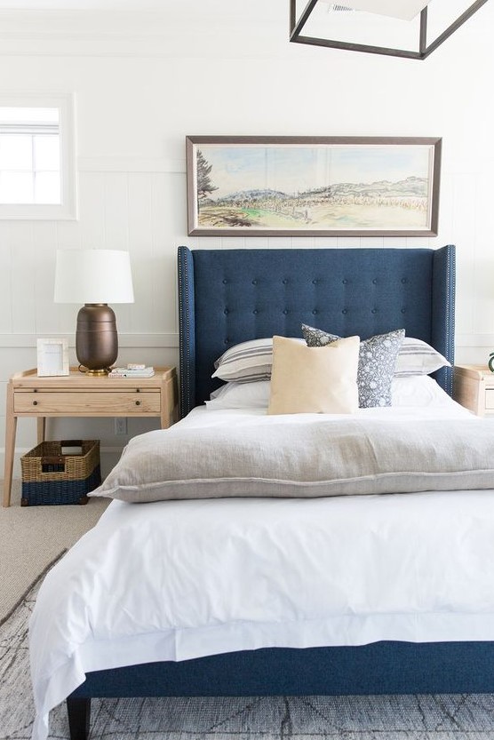 a-modern-coastal-bedroom-with-a-blue-bed-printed-textiles-a-large-artwork-wooden-furniture-a-basket-for-storage.jpg