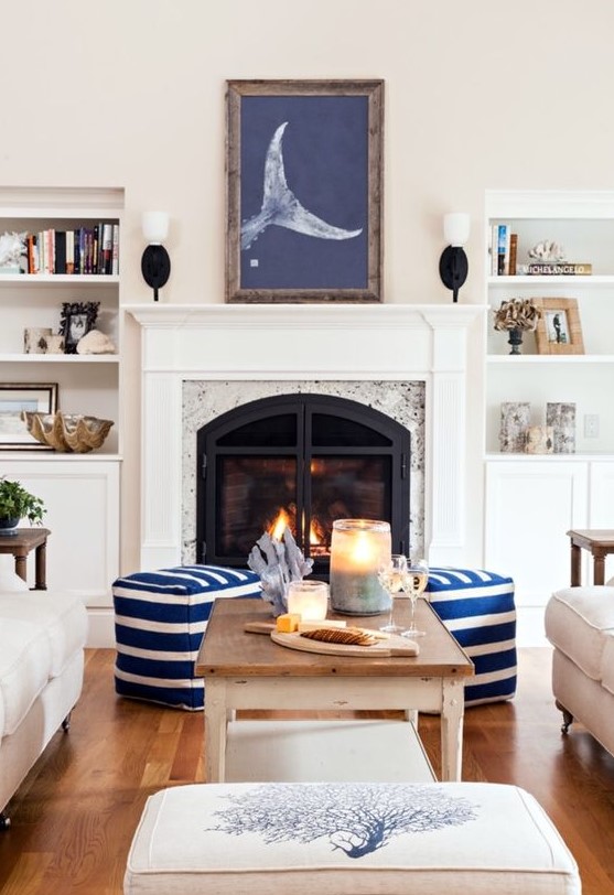 a modern coastal living room with white furniture, striped ottomans, decorative seashells and corals plus an artwork