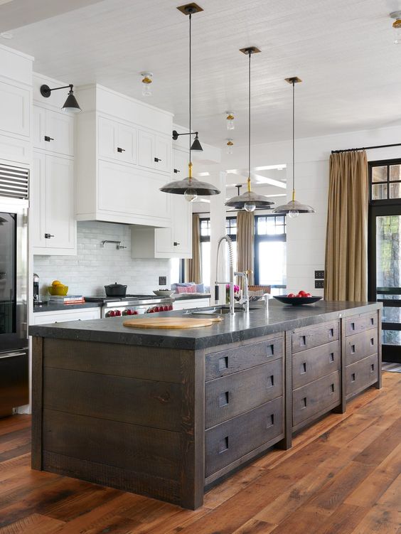 a modern kitchen with white cabinets, a white subway tile backsplash, a dark-stained kitchen island and pendant lamps