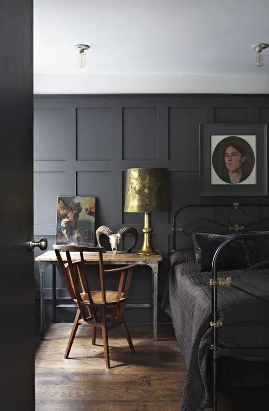 a moody Gothic bedroom with gold touches and vintage furniture, with vintage artwork and an animal skull