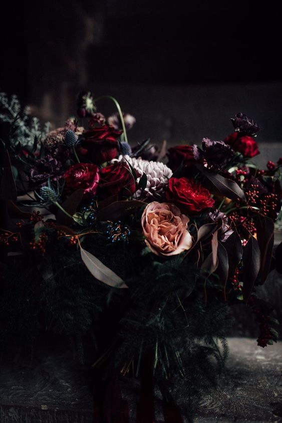a moody Halloween flower arrangement of red, pale lilac and coral blooms and greenery plus thistles is amazing