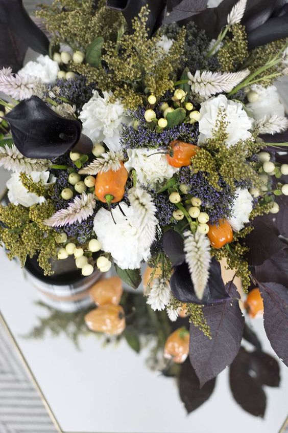 a moody Halloween flower arrangement of white blooms, berries, peppers, black callas and some greenery