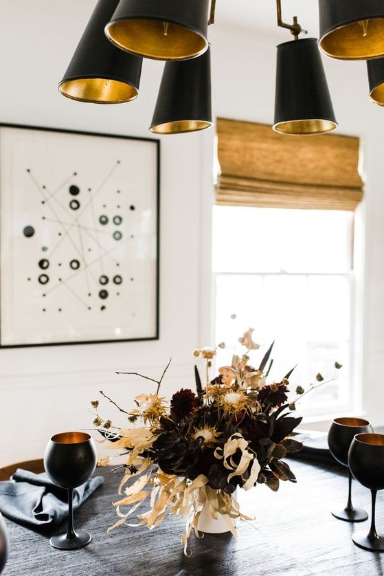 a moody floral arrangement with deep purple and burgundy blooms, branches, dried flowers and corn husks