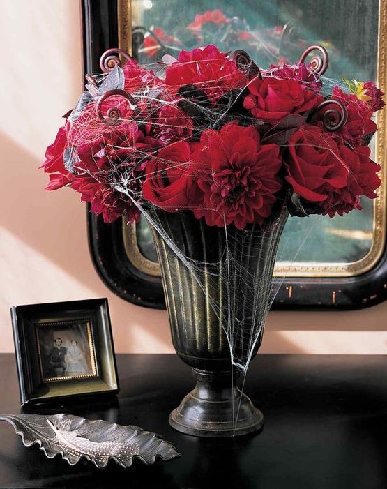 a moody vintage urn with sumptuous red blooms and some spiderweb is a traditional Halloween option that always works