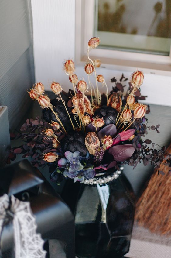 a refined and chic Halloween flower arrangement of deep purple, black blooms and some dried flowers for a decadent feel