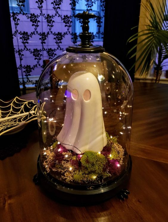 a simple Halloween cloche with moss, bold dried blooms, lights and a funky ghost figurine is a cool idea for a kids' party