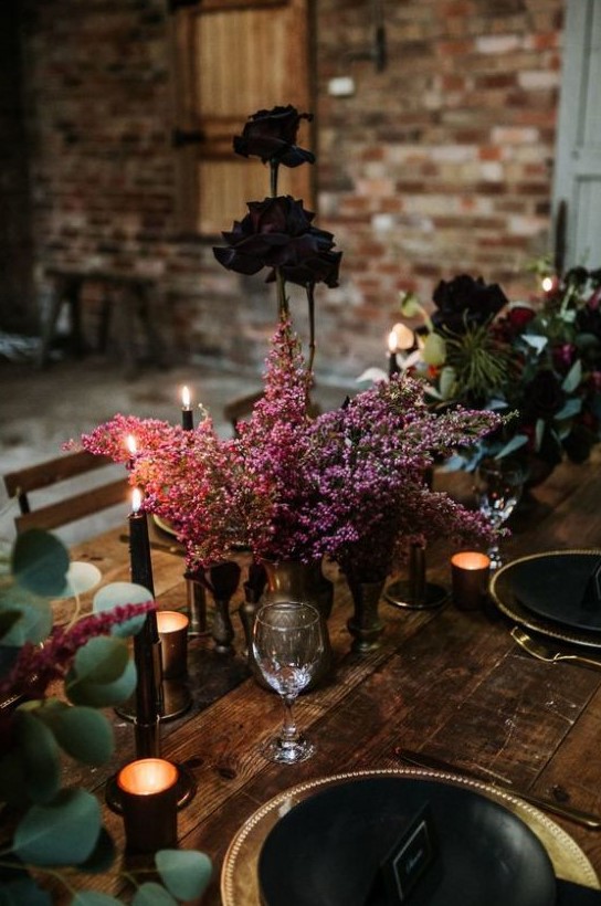 a simple yet luxurious floral Halloween centerpiece of pink blooms in a metal vase and a couple of very dark roses