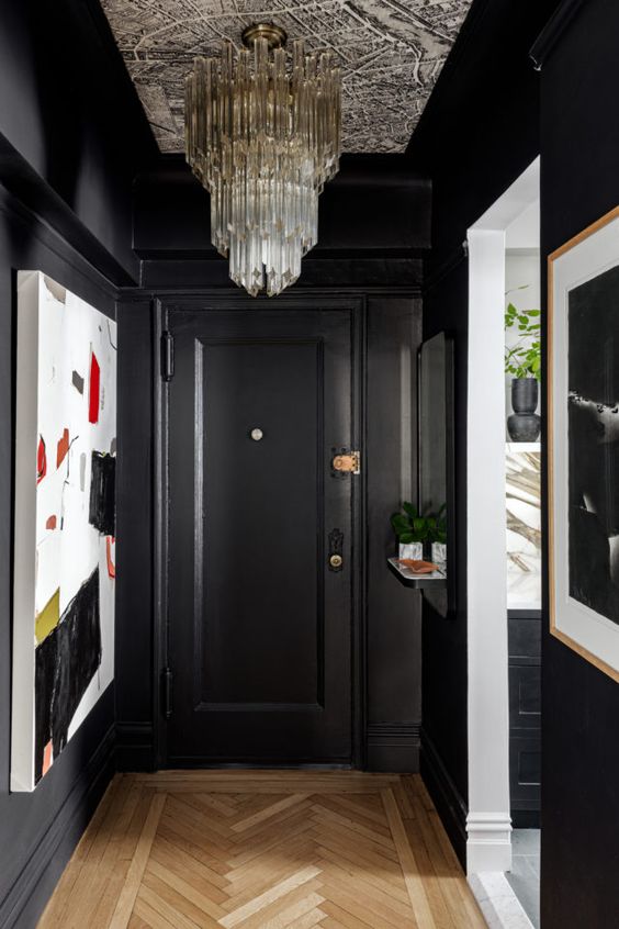 a soot entryway with a crystal chandelier, a bold artwork, potted greenery is a very sophisticated and chic space
